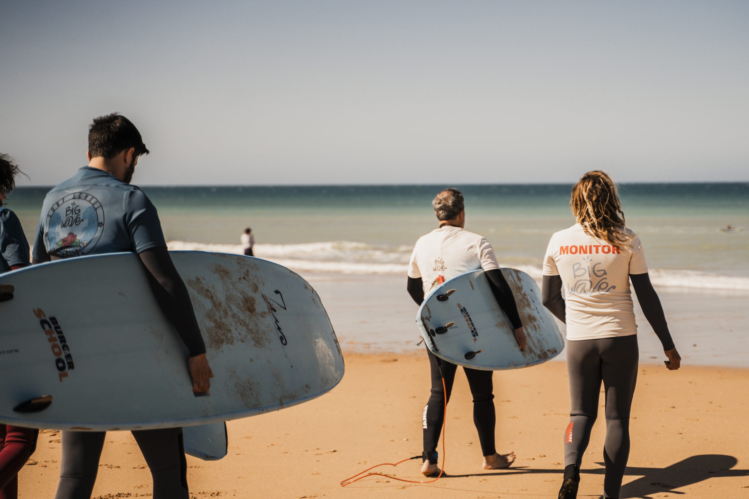 Grupo de alumnos de Big Wave caminando hacia el mar con sus tablas