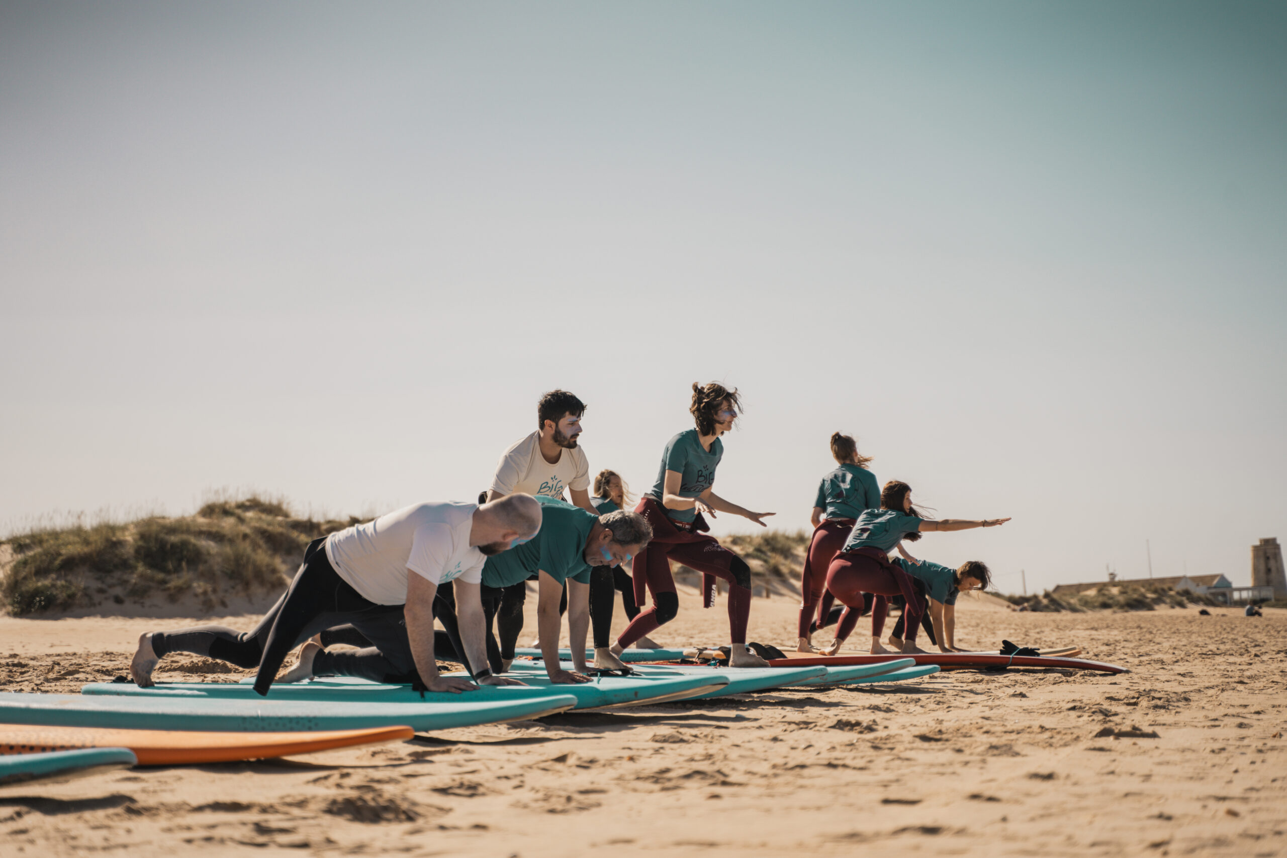 Clase de surf practicando la puesta en pie en la playa de El Palmar