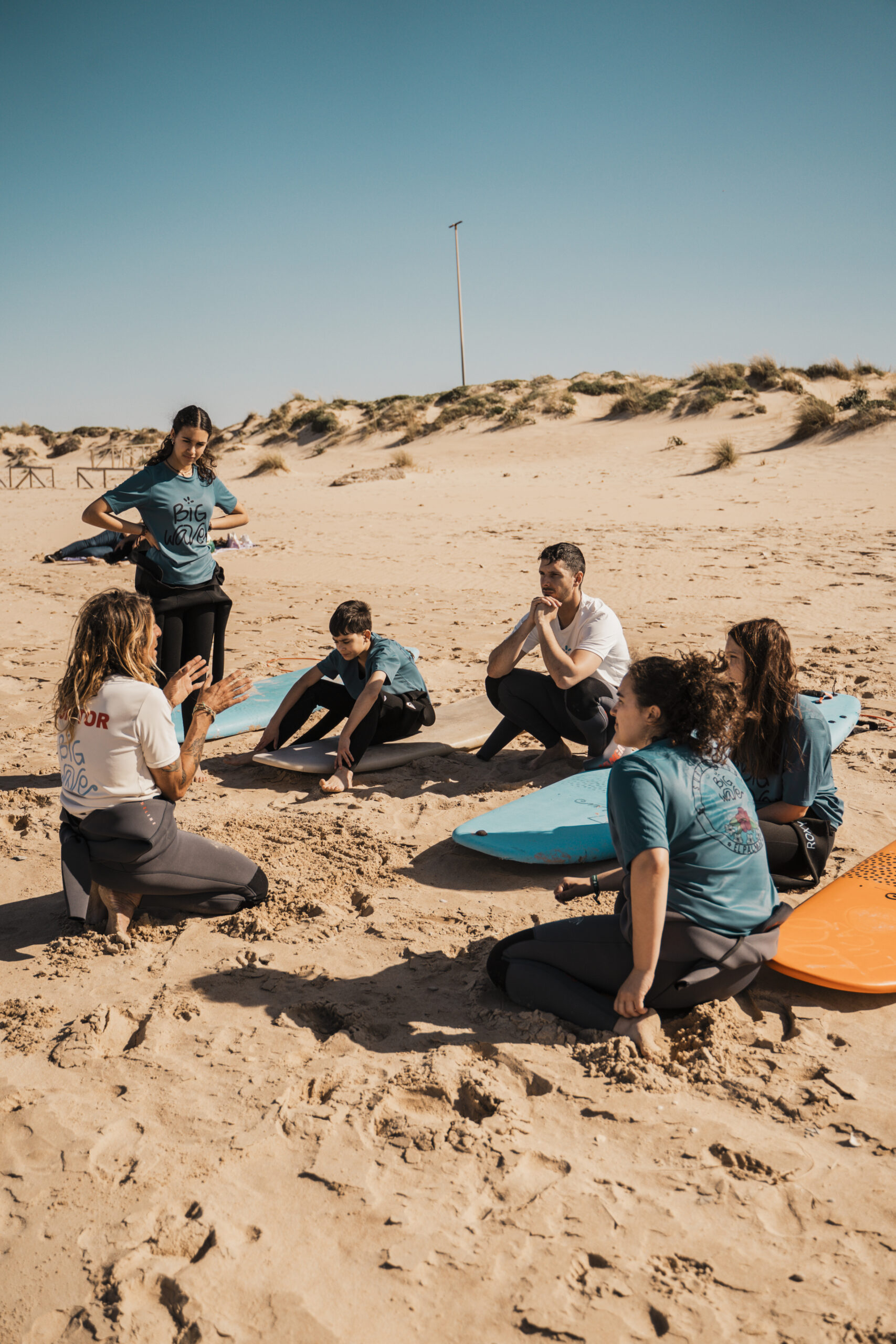 Grupo de alumnos compartiendo una sesión de surf en la playa de El Palmar