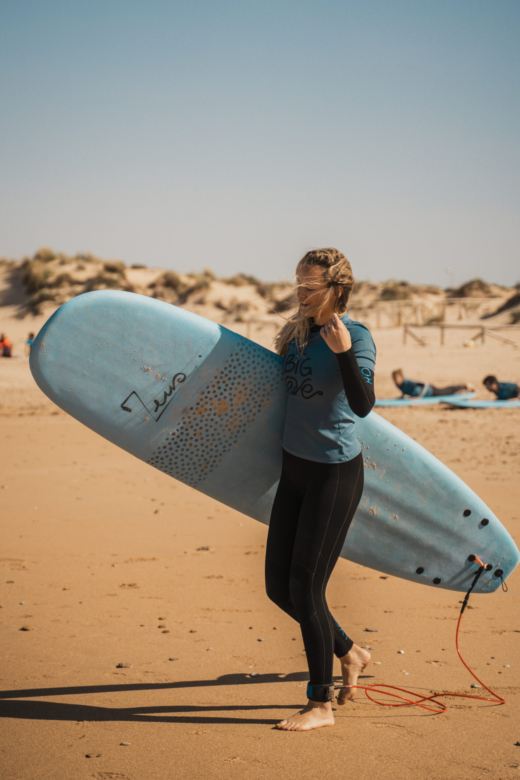 Alumna adulta con su tabla antes de una clase de surf en El Palmar