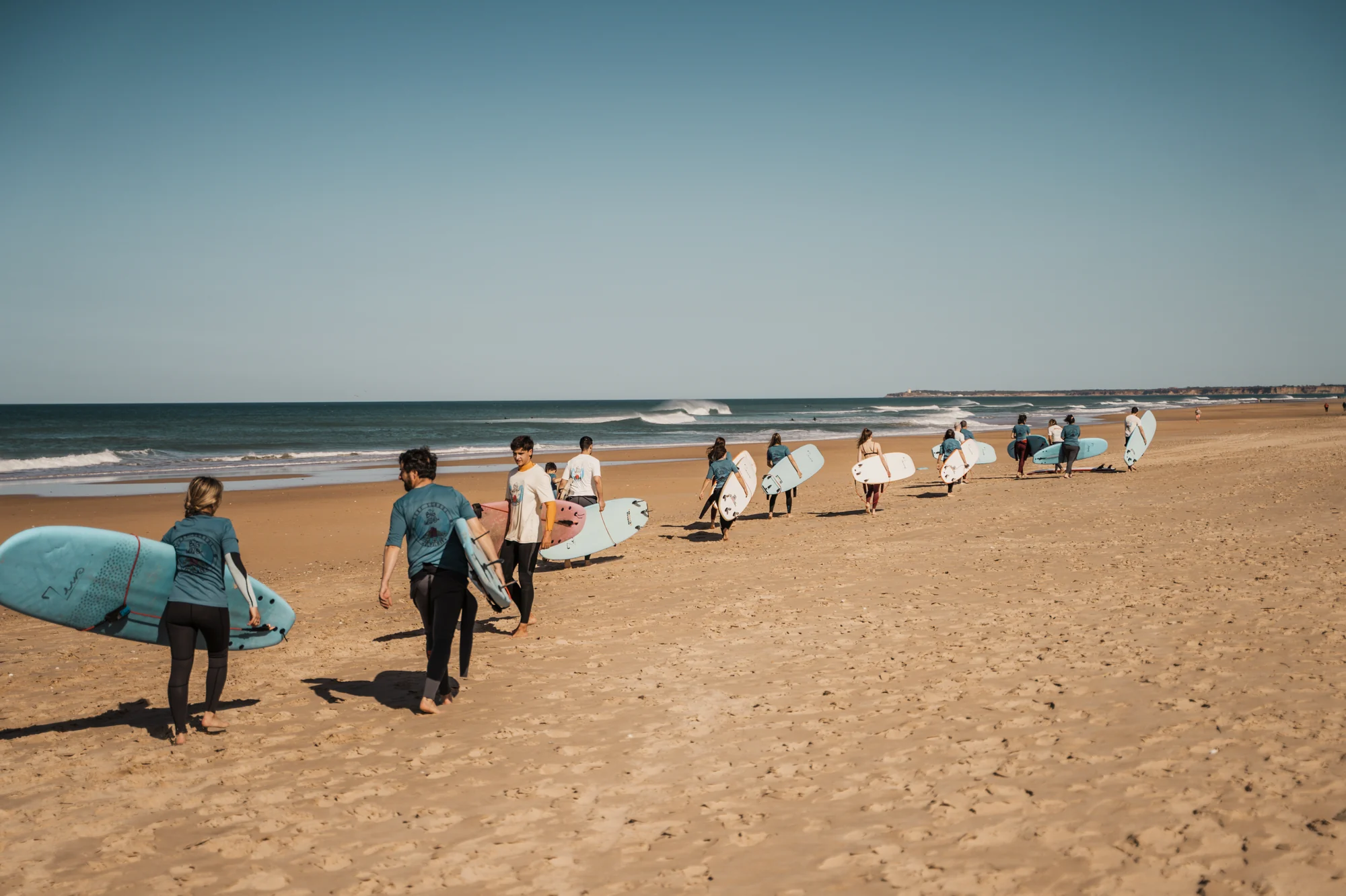 Grupo de adultos caminando con sus tablas hacia las olas de El Palmar