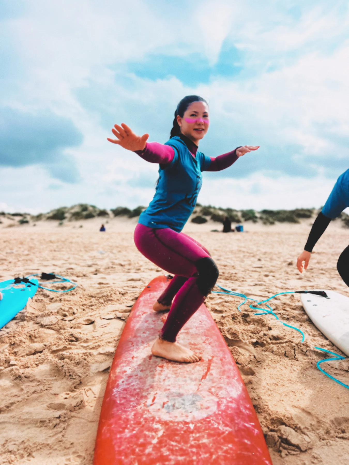 Alumna practicando la postura de surf en la playa de El Palmar