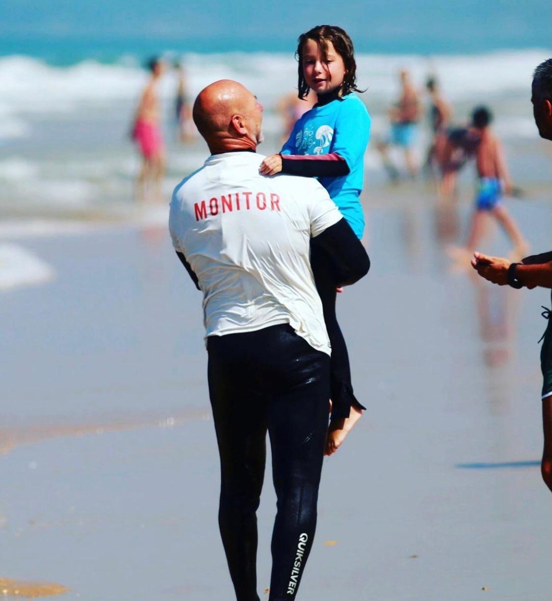 Monitor de Big Wave acompañando a una niña en la orilla de El Palmar