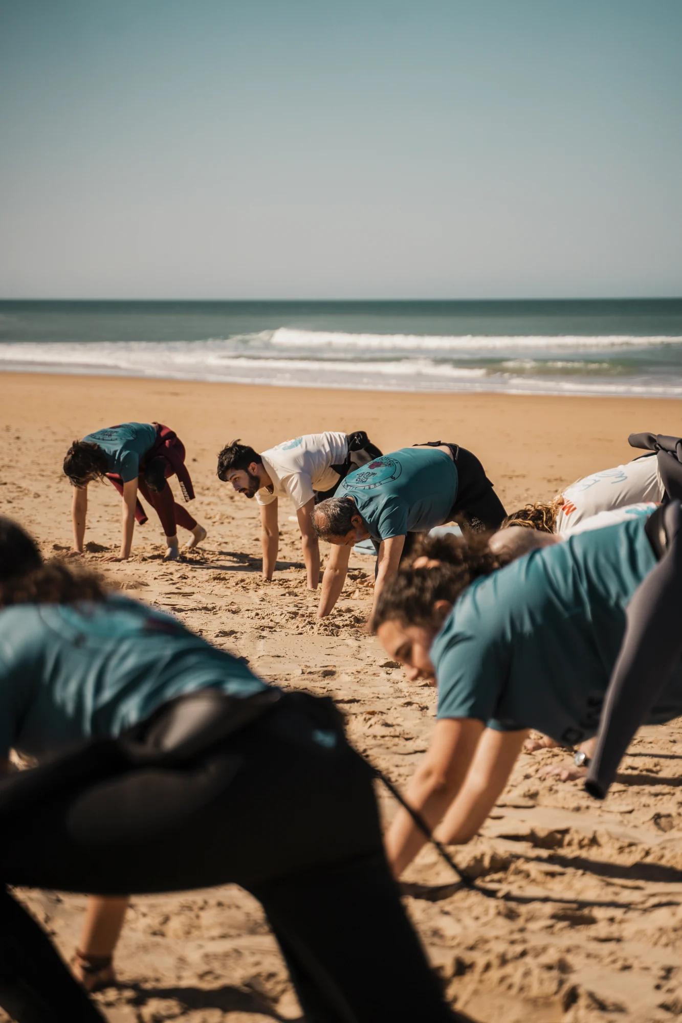Alumnos adultos preparando el cuerpo antes de una clase de surf